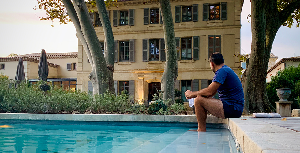 Homme assis au bord de la piscine les pieds dans l'eau